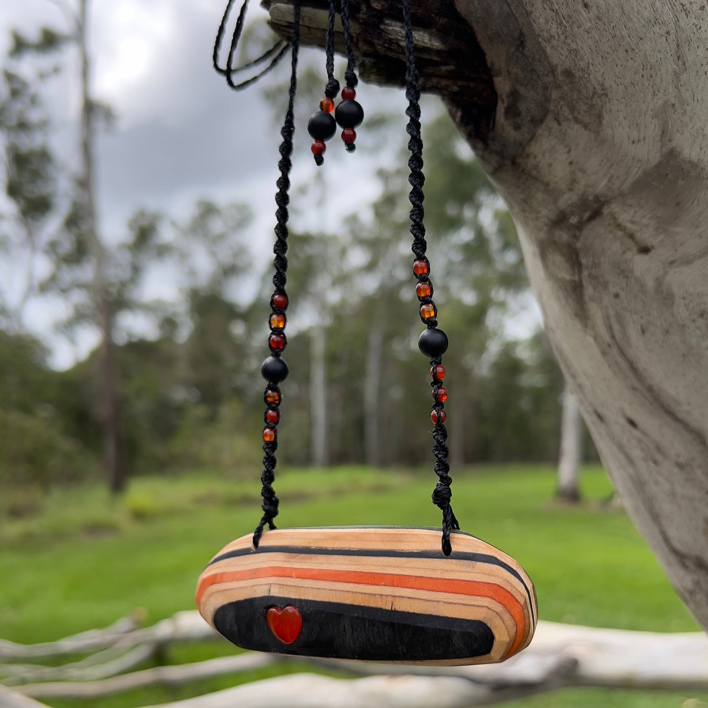 Handmade, unique recycled skateboard pendant with lush embedded Carnelian crystal heart on an adjustable macrame necklace cord woven with Obsidian and Carnelian.