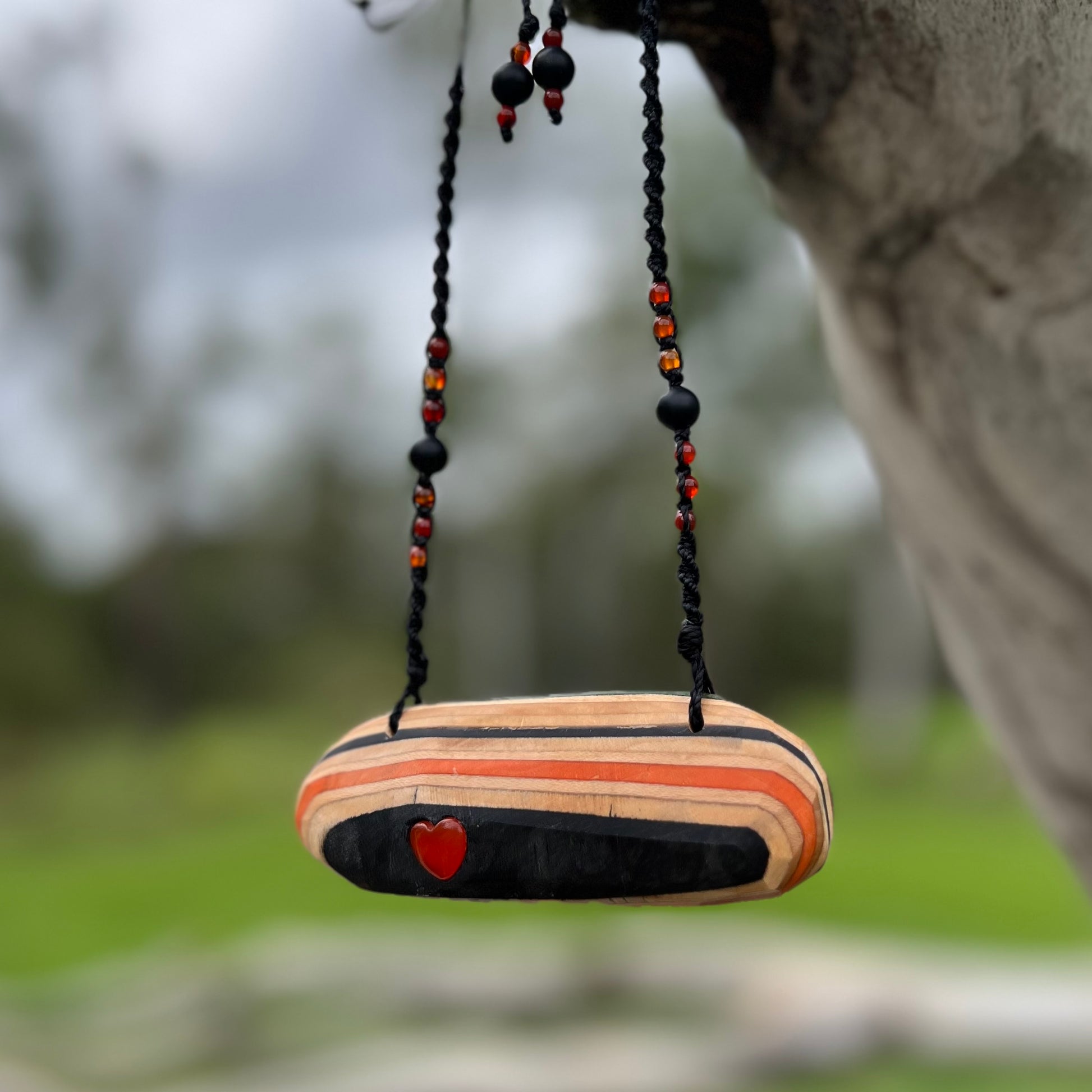 Handmade, unique recycled skateboard pendant with lush embedded Carnelian crystal heart on an adjustable macrame necklace cord woven with Obsidian and Carnelian.