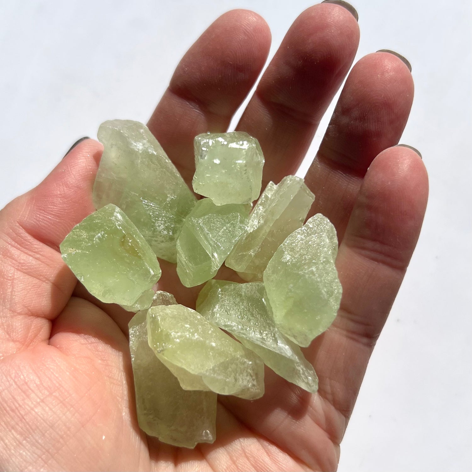 A palm full of vibrant rough green calcite pieces